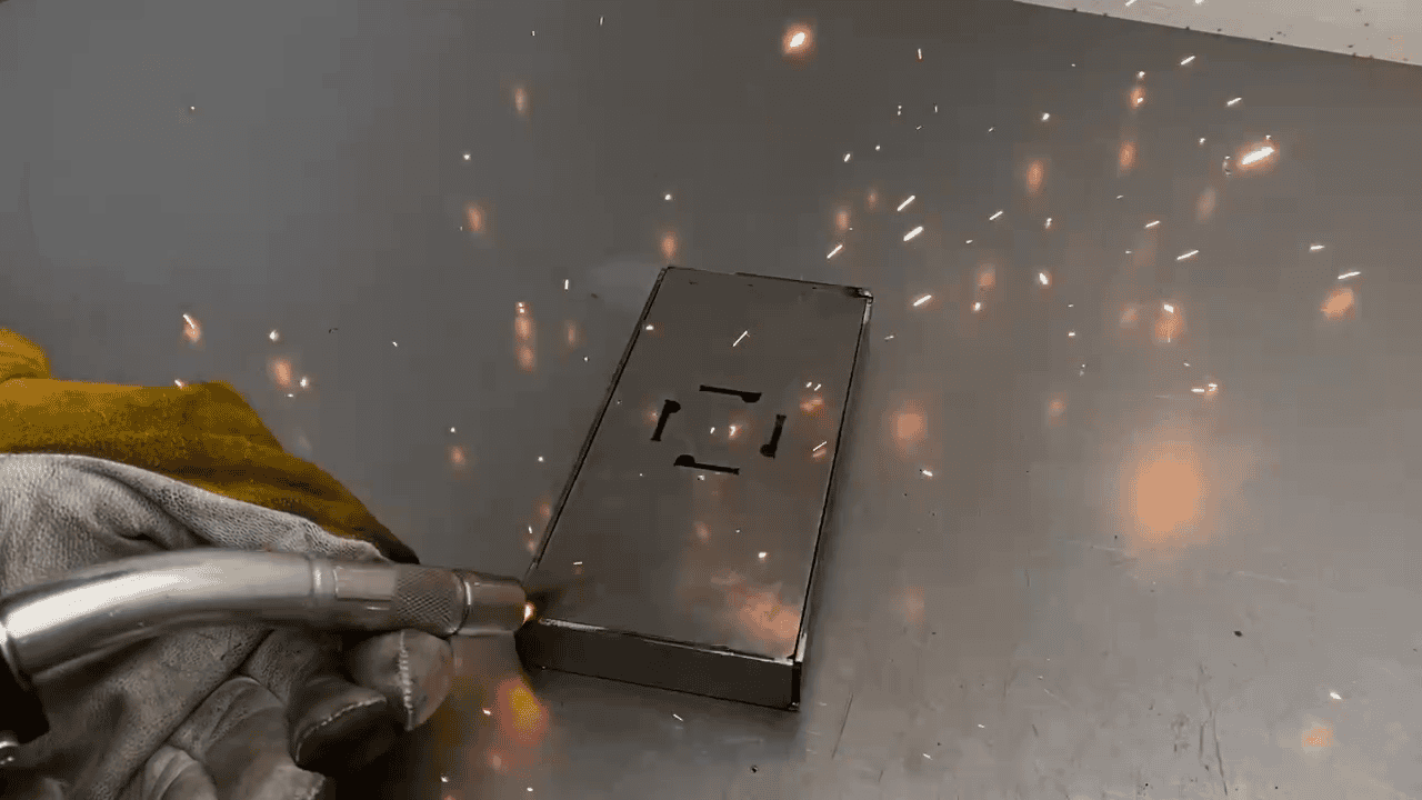 Hobby mig mag metalen bakje Een hobbylasser last met het MIG/MAG-proces een stalen bakje, waarbij er vonken zichtbaar zijn. Het lasproces zorgt voor stevige en nauwkeurige verbindingen tussen de stalen onderdelen.