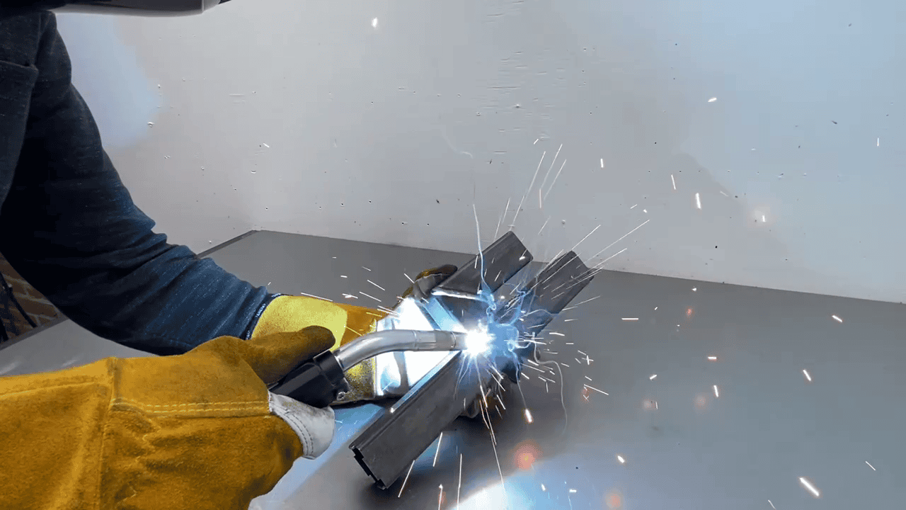 lassen van een cactus penhouder werkstuk met mig-mag Een lasser voert een MIGMAG-lasproces uit op een werkstuk, waarbij een elektrische boog en beschermgas worden gebruikt om een sterke en duurzame verbinding tussen metalen