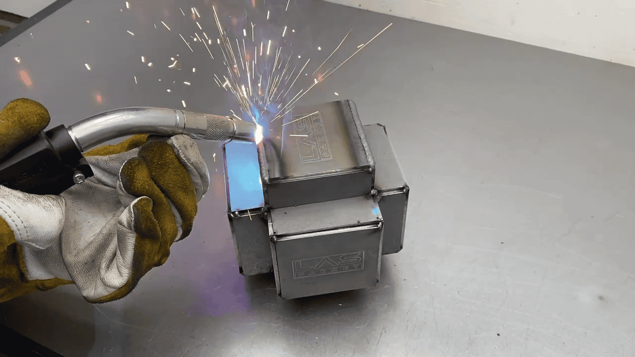 lassen van ringkubus werkstuk met mig-mag Een ringkubus-werkstuk wordt gelast met het MIG/MAG-lasproces. De lasser gebruikt een lasapparaat om nauwkeurige en sterke verbindingen te creëren tussen de metalen onderdelen. Vonken en de typische smeltplas zijn zichtbaar tijdens het lassen, wat de vakmanschap en precisie van het proces benadrukt.